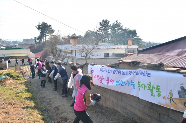 인간띠를 만든 부여군청 6개 동호회 회원들이 어려운 이웃에게 연탄을 전달하고 있다.(사진=부여군 제공)