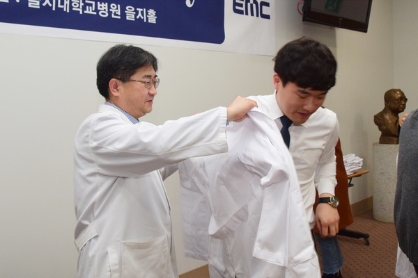18일 김하용 원장이 의사를 상징하는 흰 가운을 을지대학교 의학과 3학년 학생에게 입혀주고 있다.