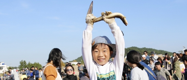 지난해 대회에 참가한 한 어린이가 물고기잡기 체험행사에서 바다장어를 잡아 즐거워 하며 장어를 하늘 높이 들어보이고 있다
