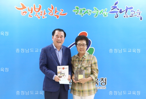 ‘요리는 감이여’ 참여 어르신을 대표해 김용선 할머니가 김지철 교육감에게 책을 전달하고 있다.