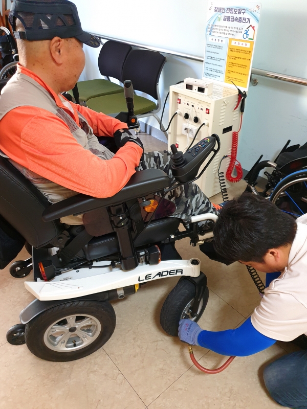 당진시장애인복지관 내 장애인전동보장구 공용충전기에서 휠체어에 바람을 넣고 있는 장면