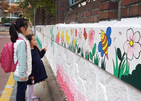 월평3동 갑천초등학교 담장에 그려진 벽화를 하교하는 아이들이 흥미롭게 보고있다