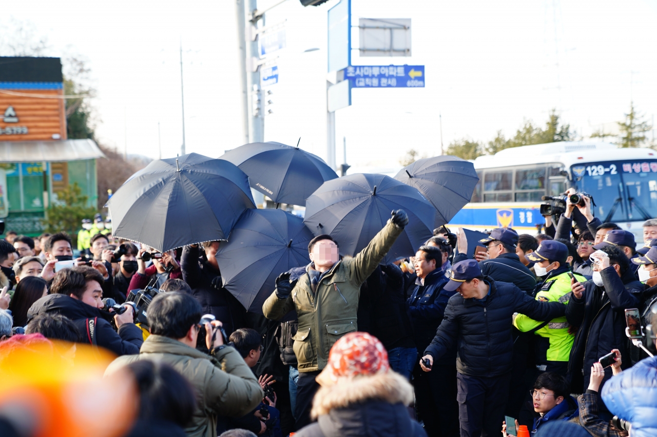 아산 격리시설 인근 주민들이 진영 행정안전부 장관과 양승조 지사에게 계란을 투척하자 경찰이 우산으로 막고 있다.