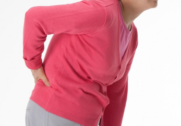 한 중년 여성이 척추관협착증으로 허리 통증을 느끼고 있다.
