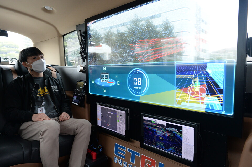 ETRI 연구진이 개발한 자율주행 셔틀버스 '오토비' 내 투명 OLED 디스플레이로 AR 실감 가이드 기술을 시연하는 모습.
