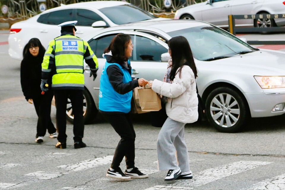 현대제철 관계자가 경찰의 보호속에 수험장으로 입실하는 수험생에게 격려물품을 전달하고 있다. 현대제철 제공.