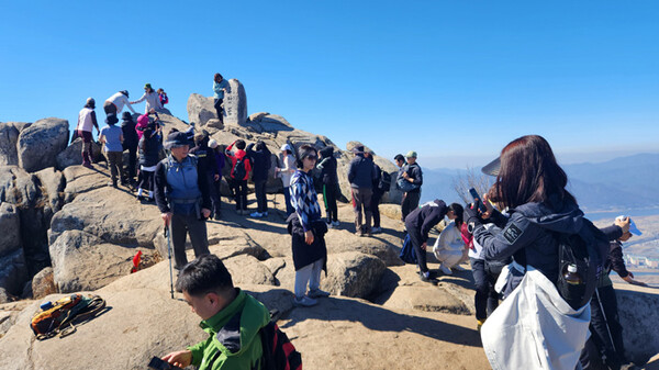 많은 등산객들이 정상석과 사진을 찍으려 기다리고 있다.