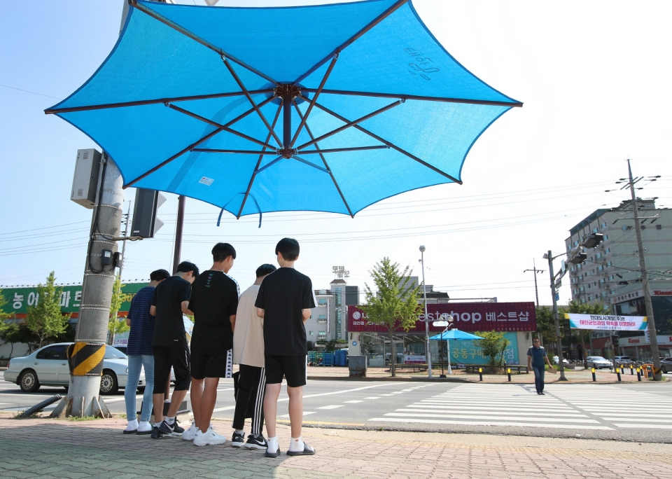 무더위가  지속되고 있어 온열질환에 대한 각별한 주의가 요구된다. 시민들이 횡단보도에 설치된 그늘막에서 햇빛을 피하고 있다. 자료사진. 
