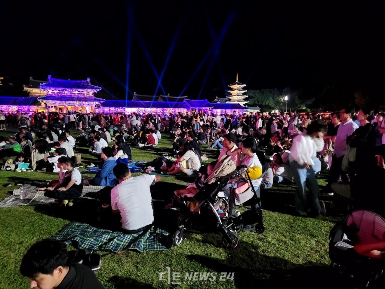 관광객들이 백제문화단지 안 잔디밭에 돗자리를 펴고 공연을 관람하고 있다. 김다소미 기자. 