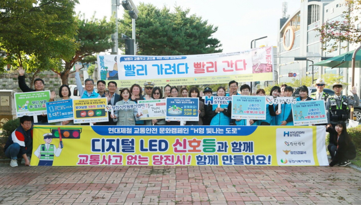 현대제철 당진제철소 임직원들이 10일 아침 복지타운 사거리에 설치한 디지털 LED 신호등 아래에서 교통 안전 캠페인을 실시하고 관계자들과 함께 기념 사진을 찍고 있다. 현대제철 당진제철소