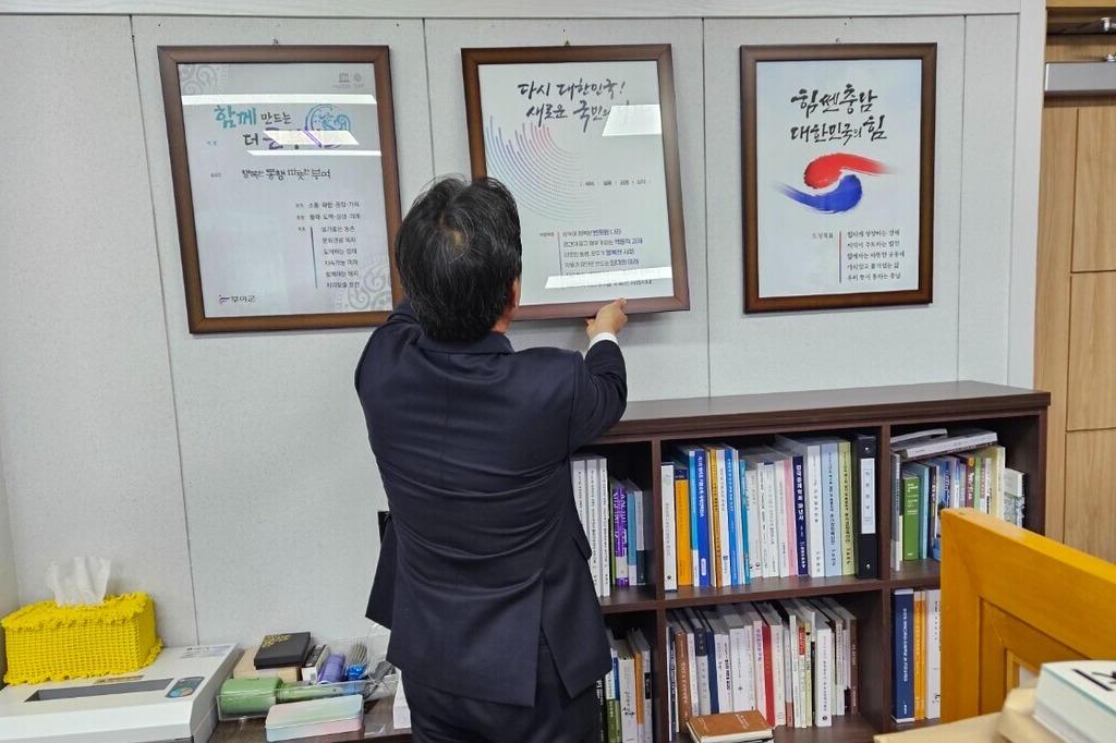 박 군수가 군수실에 걸려 있는 윤석열 정부의 국정 목표가 담긴 액자를 직접 떼어 내고 있다. 김다소미 기자. 