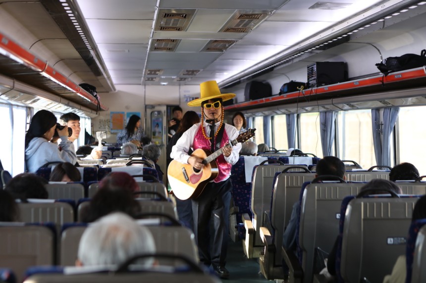 충남레트로 낭만열차 객실 모습, 분위기를 한 껏 띄우는 관계자가 통기타를 매고 참가자들에게 복고 음악을 선사한다. 충남문화관광재단 제공. 