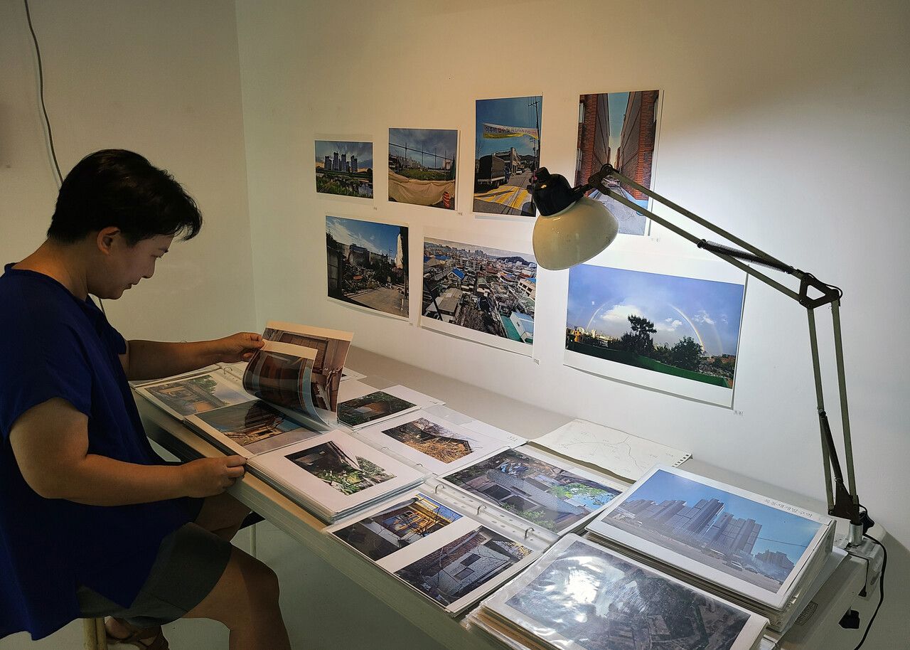 여 작가가 지난 7년 간 대전 재개발지구 현장을 돌며 찍은 사진을 펼쳐보고 있다. 한지혜 기자.