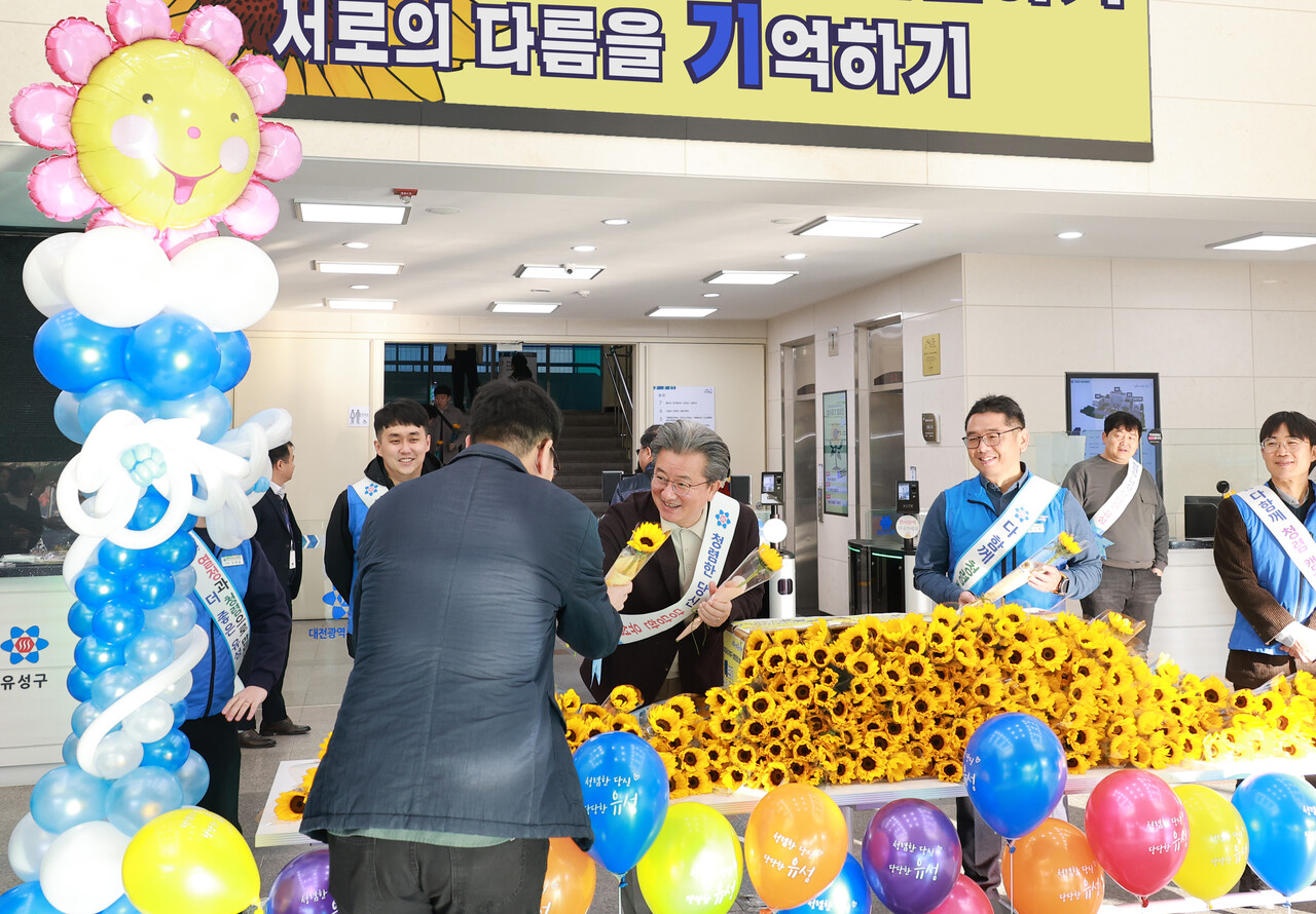 14일 유성구청 본관 로비에서 정용래 유성구청장이 출근하는 직원에게 해바라기꽃을 전달하고 있다. 유성구 제공. 