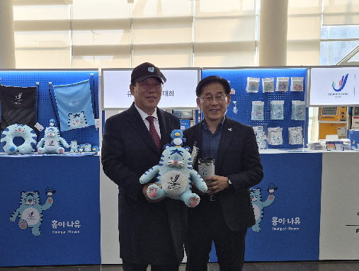 2027 충청 유니버시아드대회 조직위원회가 24일 세종시청 1층 로비에 공식 상품 팝업 부스를 설치하고 20여 종의 굿즈를 선보이는 이벤트를 개최했다. 행사장을 찾은 최민호 세종시장과 조직위 이창섭 부위원장이 굿즈를 살펴보고 있다. / 조직위 제공